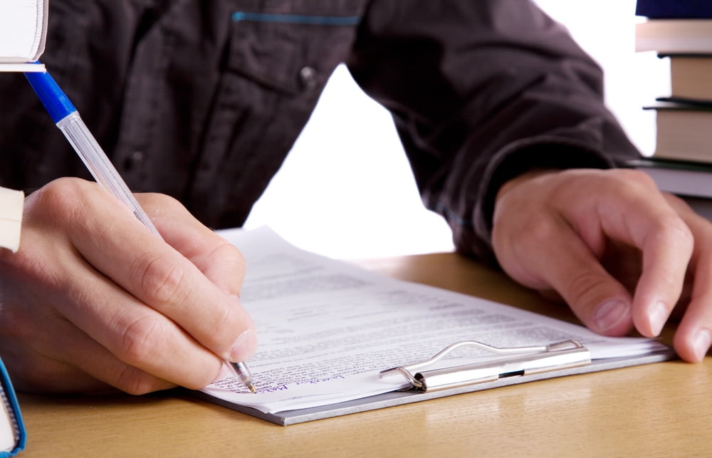 Seated man filling out a form on a clipboard