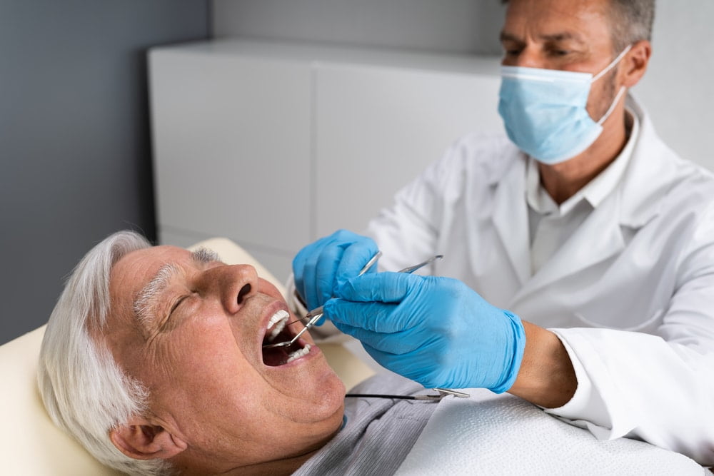 Elderly man in chair receiving treatment from a dentist