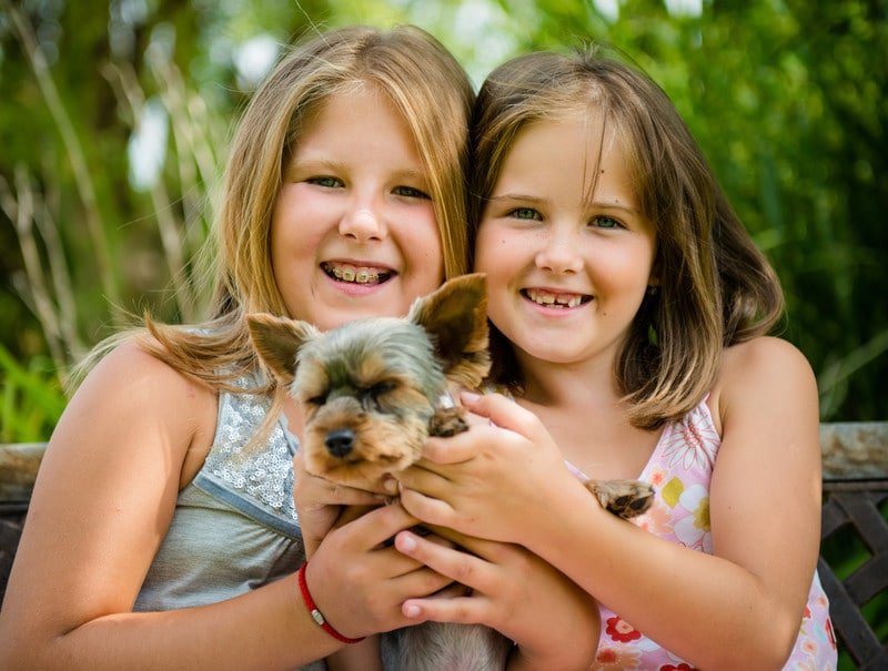 Happy smiling girls holding their dog